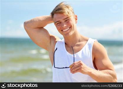 summer holidays and people concept - happy smiling young man with sunglasses on beach. smiling young man with sunglasses on summer beach