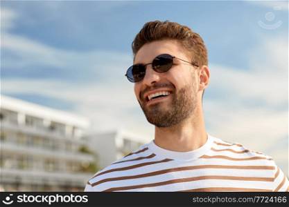 summer holidays and people concept - portrait of young man in sunglasses on beach in tallinn, estonia. young man in sunglasses on summer beach