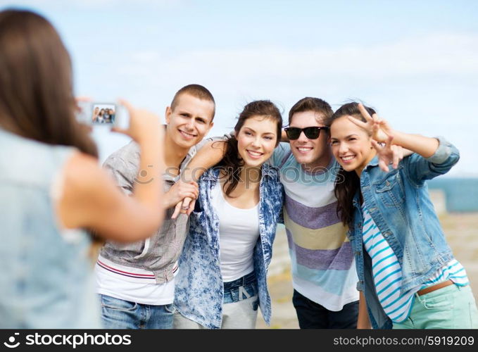 summer holidays and technology concept - group of teenagers taking photo outside. teenagers taking photo outside