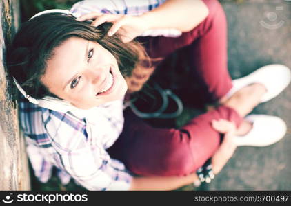 summer holidays and technology concept - teenage girl with headphones listening to music outside