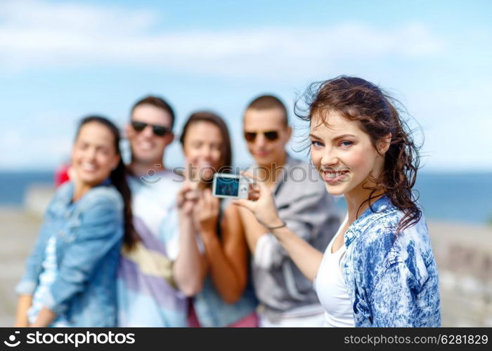 summer holidays and teenage concept - group of happy teenagers taking photo outside