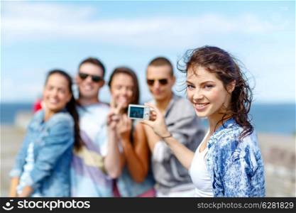 summer holidays and teenage concept - group of happy teenagers taking photo outside