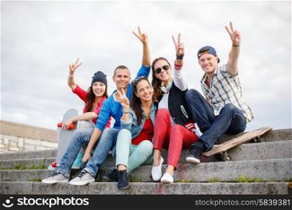 summer holidays and teenage concept - group of smiling teenagers hanging outside and showing v-sing. group of smiling teenagers hanging out