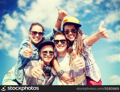 summer holidays and teenage concept - group of smiling teenagers in sunglasses hanging outside and showing thumbs up