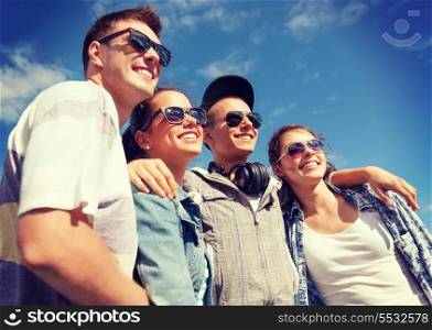 summer holidays and teenage concept - group of smiling teenagers in sunglasses hanging outside