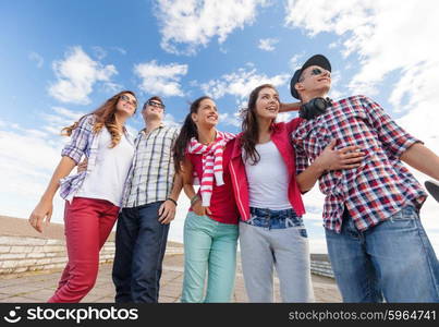 summer holidays and teenage concept - group of smiling teenagers in sunglasses hanging outside. smiling teenagers in sunglasses hanging outside