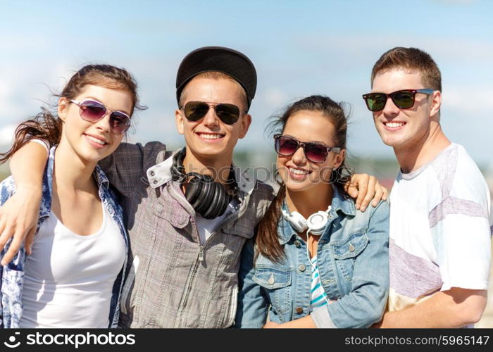 summer holidays and teenage concept - group of smiling teenagers in sunglasses hanging outside. smiling teenagers in sunglasses hanging outside