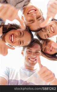 summer holidays and teenage concept - group of smiling teenagers looking down and showing thumbs up