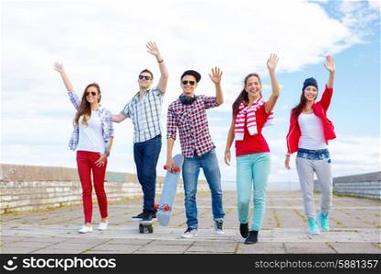 summer holidays and teenage concept - group of smiling teenagers waving hands outside