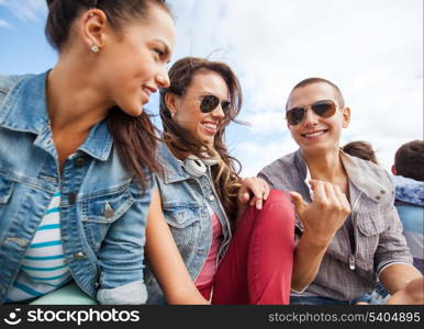 summer holidays and teenage concept - group of teenagers hanging out outside