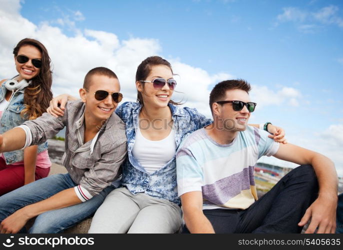 summer holidays and teenage concept - group of teenagers hanging out outside