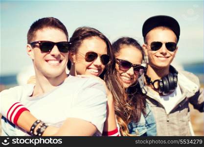 summer holidays and teenage concept - group of teenagers hanging out outside