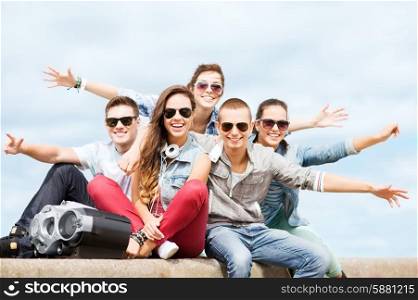 summer holidays and teenage concept - group of teenagers hanging out outside