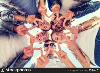 summer holidays and teenage concept - group of teenagers showing peace or victory gesture