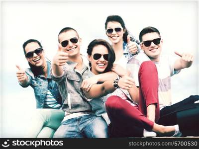 summer holidays and teenage concept - group of teenagers showing thumbs up outside