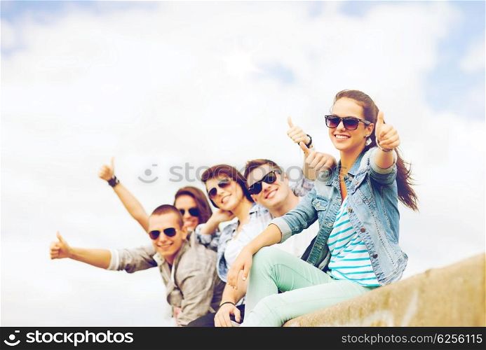 summer holidays and teenage concept - group of teenagers showing thumbs up. teenagers showing thumbs up