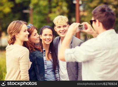 summer holidays and teenage concept - group of teenagers taking photo outside