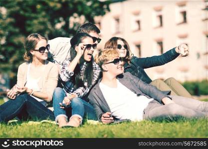 summer holidays and teenage concept - group of teenagers taking photo outside with smartphone