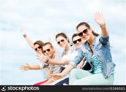 summer holidays and teenage concept - group of teenagers waving hands