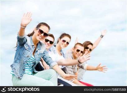summer holidays and teenage concept - group of teenagers waving hands
