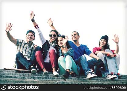 summer holidays and teenage concept - group of teenagers waving hands outside