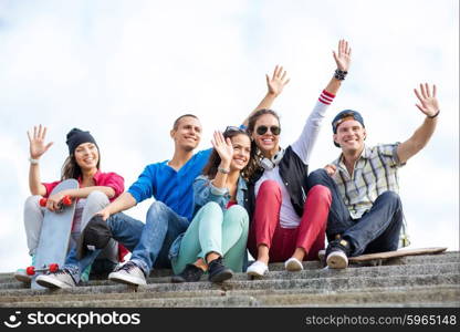 summer holidays and teenage concept - group of teenagers waving hands outside. group of teenagers waving hands