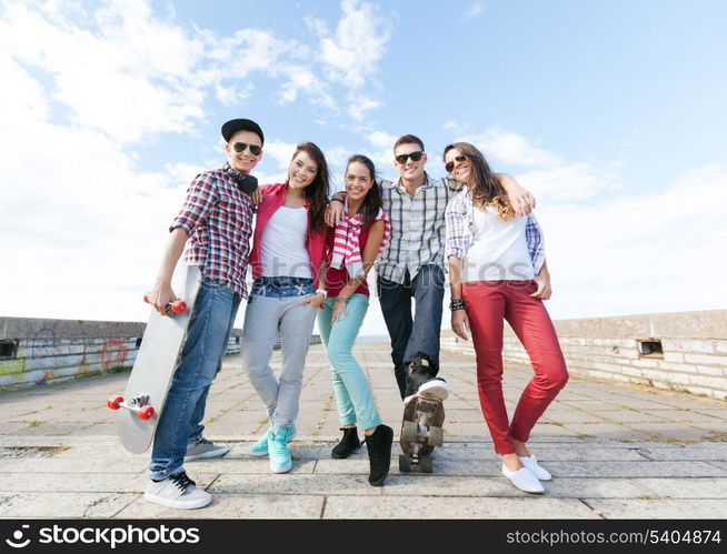 summer holidays and teenage concept - group of teenagers with skates outside