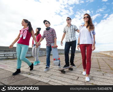 summer holidays and teenage concept - group of teenagers with skates outside