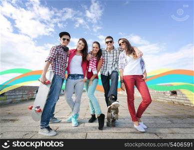 summer holidays and teenage concept - group of teenagers with skates outside