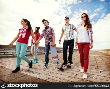 summer holidays and teenage concept - group of teenagers with skates outside