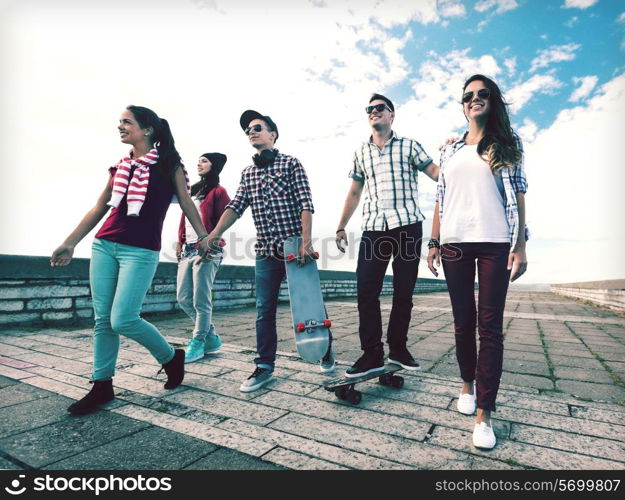 summer holidays and teenage concept - group of teenagers with skates outside