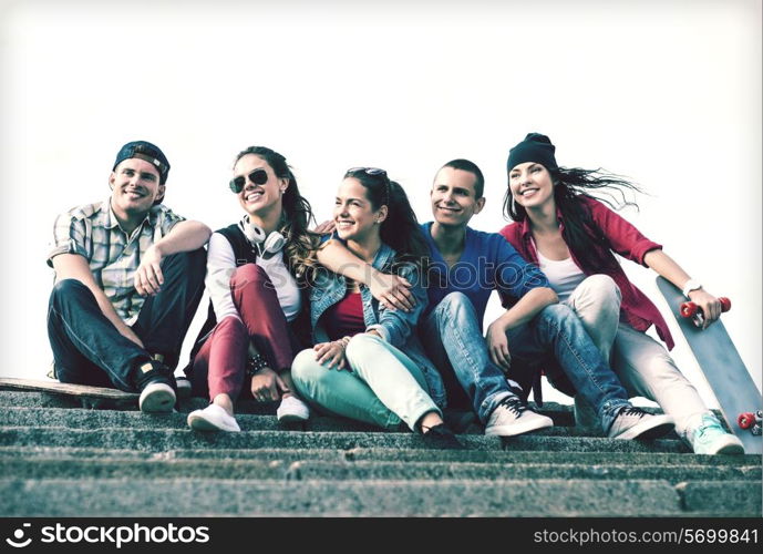 summer holidays and teenage concept - group of teenagers with skates outside