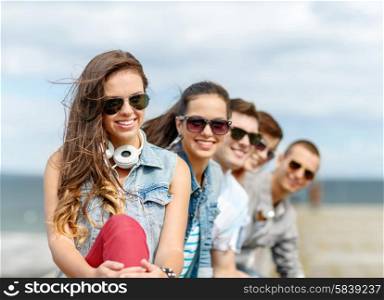 summer holidays and teenage concept - smiling teenage girl in sunglasses hanging out with friends outdoors. smiling teenage girl hanging out with friends