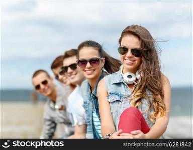summer holidays and teenage concept - smiling teenage girl in sunglasses hanging out with friends outdoors