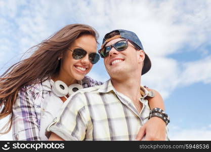 summer holidays and teenage concept - smiling teenagers in sunglasses having fun outside. smiling teenagers in sunglasses having fun outside