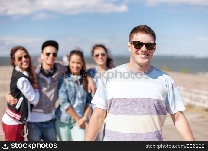 summer holidays and teenage concept - teenage boy in sunglasses hanging out with friends outside