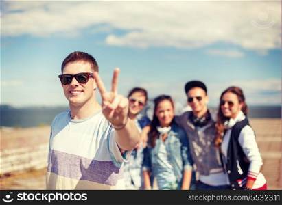 summer holidays and teenage concept - teenage boy in sunglasses hanging out with friends outside