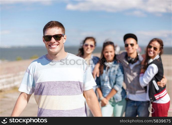 summer holidays and teenage concept - teenage boy in sunglasses hanging out with friends outside. teenage boy with sunglasses and friends outside