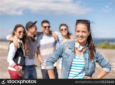 summer holidays and teenage concept - teenage girl in sunglasses and headphones hanging out with friends outside