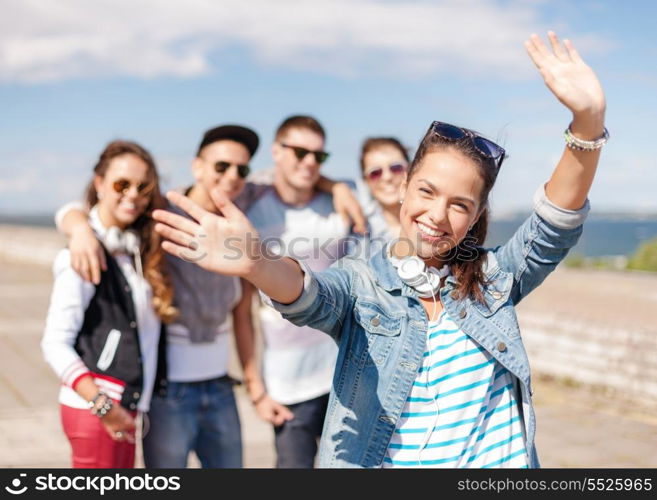 summer holidays and teenage concept - teenage girl in sunglasses and headphones hanging out with friends outside