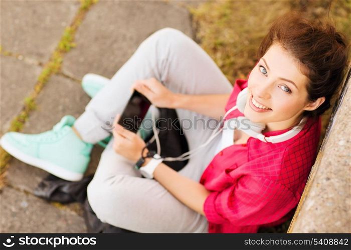 summer holidays and teenage concept - teenage girl with headphones listening to music outside