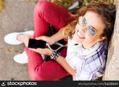 summer holidays and teenage concept - teenage girl with headphones listening to music outside