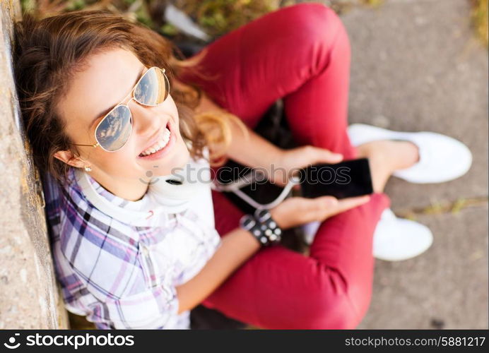 summer holidays and teenage concept - teenage girl with headphones listening to music outside