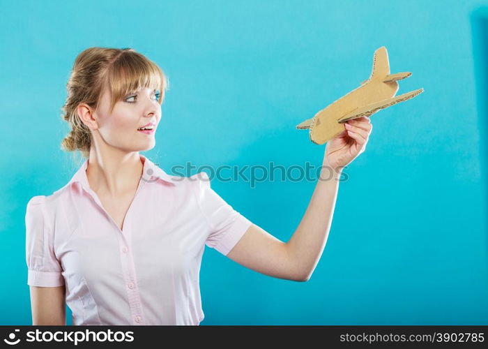 Summer holidays and tourism concept. attractive business woman enjoying life daydreaming thinking about vacation holding paper toy airplane in hand on blue