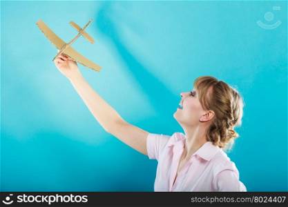 Summer holidays and tourism concept. attractive business woman enjoying life daydreaming thinking about vacation holding paper toy airplane in hand on blue