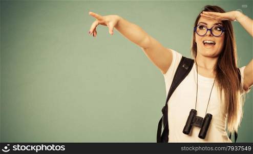 Summer holidays and tourism concept. Attractive woman long hair with backpack binocular pointing copyspace with finger filtered photo