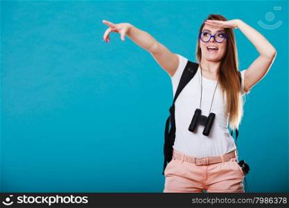 Summer holidays and tourism concept. Attractive woman long hair with backpack binocular pointing copyspace with finger on blue