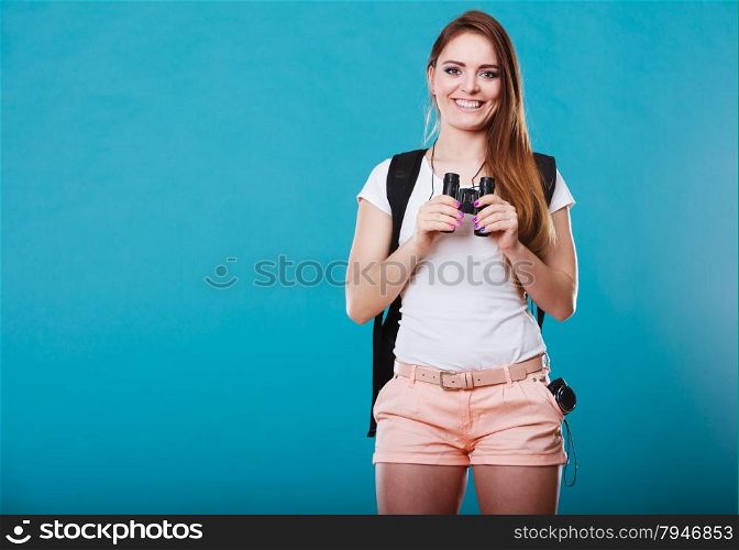 Summer holidays and tourism concept. Attractive woman long hair with backpack holding binocular on blue