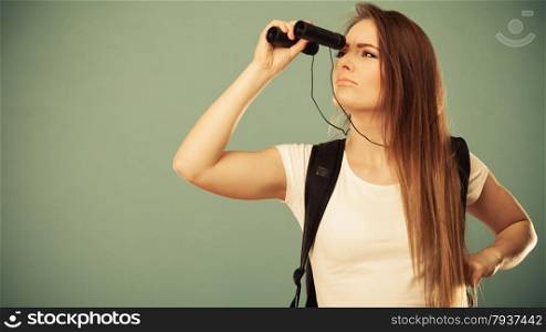 Summer holidays and tourism concept. Attractive woman long hair with backpack looking through binocular filtered photo