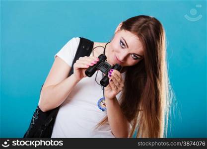 Summer holidays and tourism concept. Lovely tourist woman with backpack compass looking through binoculars on blue